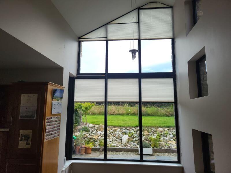 Shaped Pleated Blinds installed on a picturesque window.